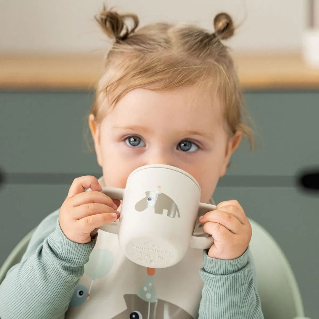 Done by Deer® Silikonski lonček s pokrovčkom in ročaji Celebration Sand Done by Deer